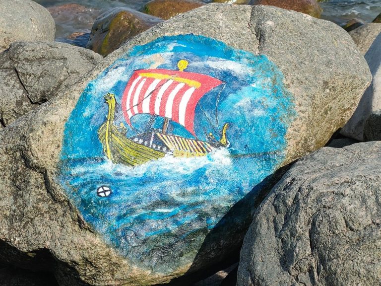 Bunter Stein mit einer Drachenboot-Malerei vor einer blauen Welle.