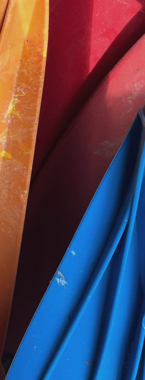 Bunte, übereinanderliegende Plastikpaddel in Orange, Rot und Blau.